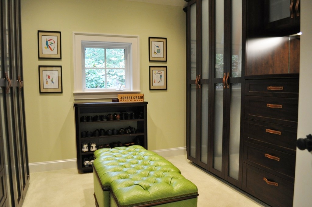 A master closet with a tufted leather ottoman in the middle