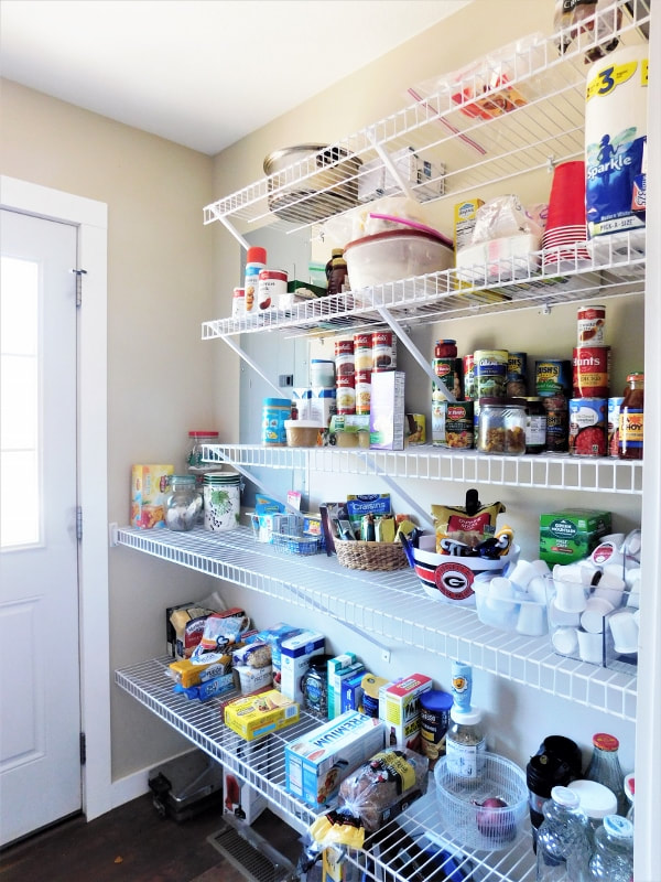 Wire shelves in a pantry, with household goods stacked on them