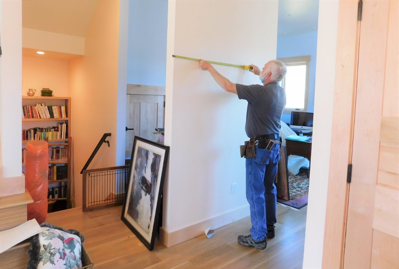 A handyman hanging art in a home in Asheville